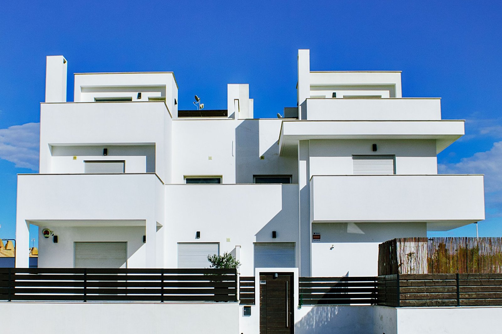 Modern white multi-storey residential building under a clear blue sky