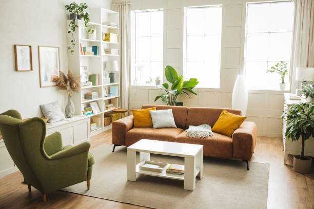 Bright, furnished living room with a leather sofa, armchair and large windows